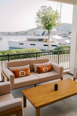 Bej koltuklar ve yastıklı koltuklar toprak setin terasında tahta bir masanın yanında duruyor. Yüksek kalite fotoğraf