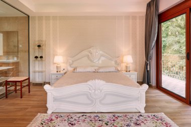 Panoramik pencereli ve banyoya cam bölmeli bir otel odasında beyaz çift kişilik yatak. Yüksek kalite fotoğraf