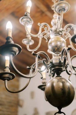 Tahta tavandan sarkan kürelerle parlayan antik bronz avize. Yüksek kalite fotoğraf