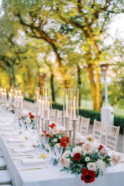 Yeşil bir parktaki çiçeklerin arasında şenlik masasında mumlar parlıyordu. Yüksek kalite fotoğraf