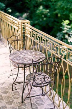 İki metal sandalye terasta yuvarlak bir masanın yanında duruyor. Yüksek kalite fotoğraf