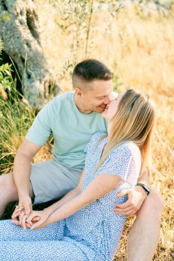 Adam bahçede kuru çimenlerde otururken neredeyse kızı öpüyordu. Yüksek kalite fotoğraf