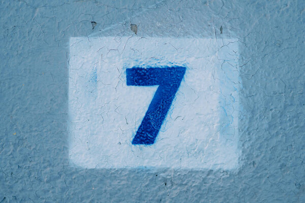 Number seven drawn on a blue wall in a rectangle. High quality photo