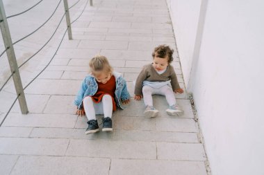 Little girl looks at her friend trying to slide down the ramp on her butt. High quality photo