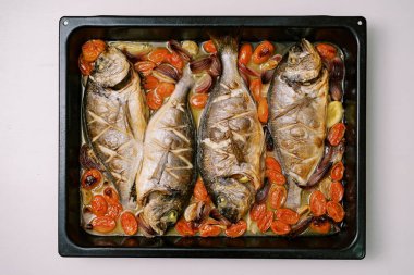 Sebzeli fırınlanmış deniz kepeği masanın üzerindeki bir yemek tepsisinin üzerinde yatıyor. Yüksek kalite fotoğraf