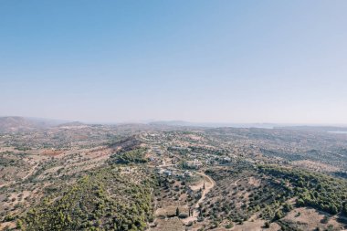 Dağların yamaçlarındaki yeşil ağaçların arasında bir otel kompleksi. Amanzoe, Mora, Yunanistan. Drone. Yüksek kalite fotoğraf