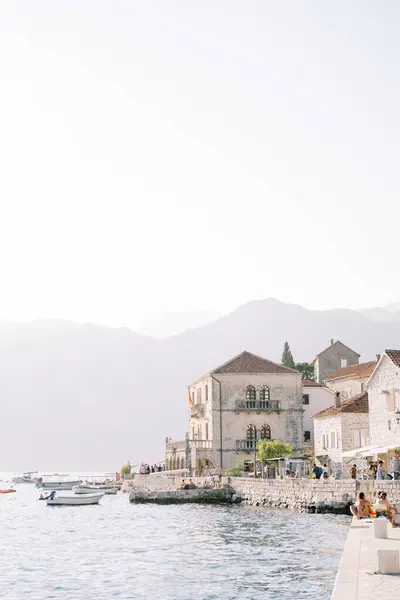 stock image Tourists sit on the piers of Perast and walk along the embankment. Montenegro. High quality photo