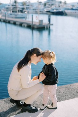 Annem iskelede çömelmiş küçük bir kızla alnına dokunuyor ve ellerini tutuyor. Yüksek kalite fotoğraf