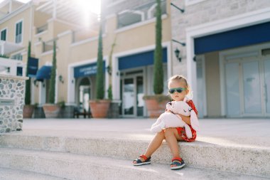 Kaldırımda pembe oyuncak tavşanla oturan küçük kız. Yüksek kalite fotoğraf