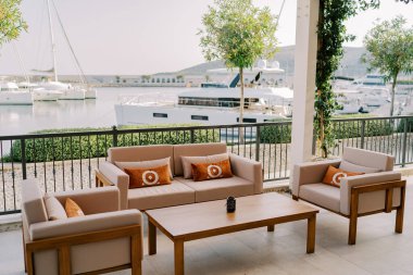 Yastıklı kanepe ve koltuklar gezinti güvertesindeki bir terasta ahşap bir masanın yanında duruyor. Yüksek kalite fotoğraf