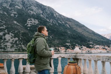 Termal fincanlı bir adam, balyozun yanında duruyor ve mesafeye bakıyor. Yan görüş. Yüksek kalite fotoğraf