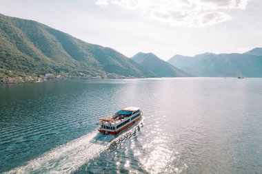 Yolcu keşif gemisi arka planda bir dağ silsilesiyle körfez boyunca hareket eder. Drone. Yüksek kalite fotoğraf