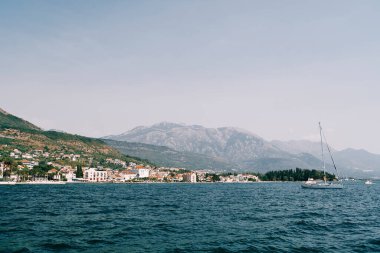 Denizde yelkenli bir yatla dağlık bir sahilin arka planına karşı. Yüksek kalite fotoğraf