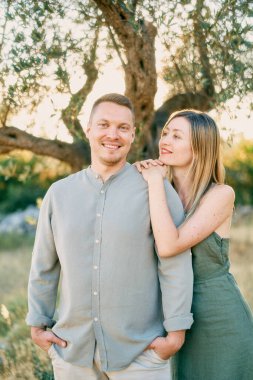 Genç kadın ellerini ve çenesini gülümseyen adamın omzuna koydu. Yüksek kalite fotoğraf