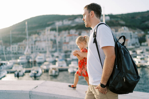 Dad leads a little girl holding her hand along the stone fence of the luxury marina embankment. High quality photo — Stock Image Dad Leads Little Girl Holding Her Hand Stone Fence Luxury Royalty Free Stock Images