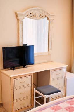 Televizyon, otel odasındaki sandalyenin yanındaki aynanın yanındaki dolapta duruyor. Yüksek kalite fotoğraf