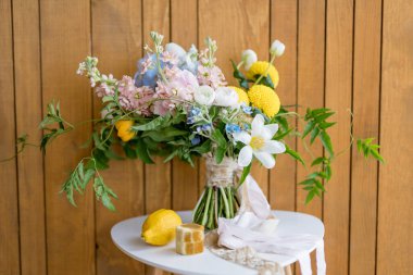 Limon ve yüzüklü ahşap bir kutu duvardaki taburede gelin buketinin yanında duruyor. Yüksek kalite fotoğraf