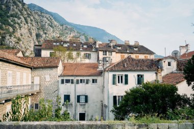 Pencerelerinde panjurları ve dağların eteklerinde kırmızı çatıları olan antik taş evler. Kotor, Karadağ. Yüksek kalite fotoğraf