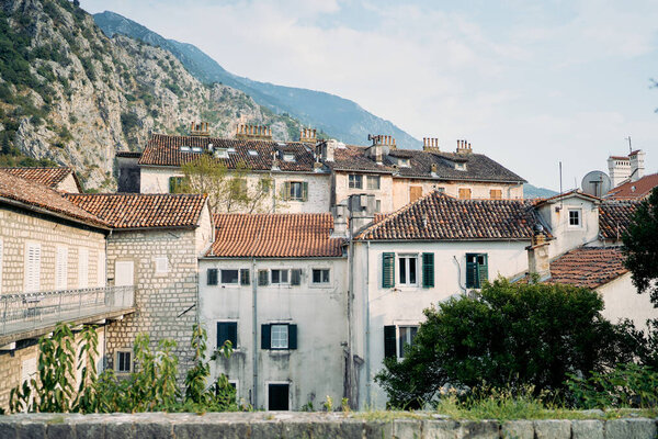 Ancient stone houses with shutters on the windows and red roofs at the foot of the mountains. Kotor, Montenegro. High quality photo — Stock Image Ancient Stone Houses Shutters Windows Red Roofs Foot Mountains Kotor Stock Image