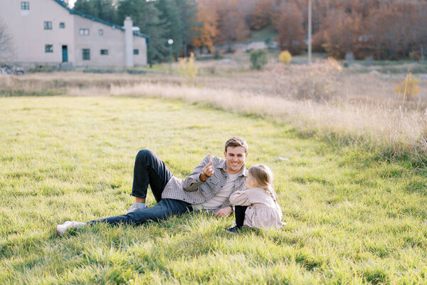 Smiling Dad Lies Clearing Shows Little Girl Sitting Next Him Royalty Free Stock Images