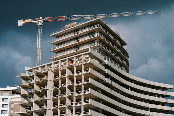 Tall tower crane above a huge skyscraper under construction against a stormy sky. High quality photo — Stock Image Tall Tower Crane Huge Skyscraper Construction Stormy Sky High Quality Royalty Free Stock Images