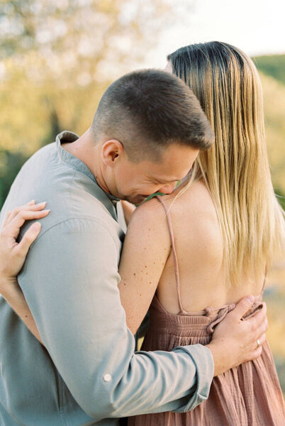 Smiling guy hugs girl by the waist, touching her shoulder with his nose. Back view. High quality photo — Stock Image Smiling Guy Hugs Girl Waist Touching Her Shoulder His Nose Royalty Free Stock Photos