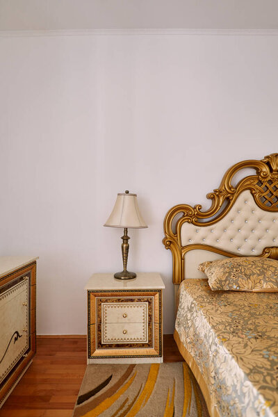 Bronze lamp with a shade on a nightstand next to a Victorian-style double bed. High quality photo — Stock Image Bronze Lamp Shade Nightstand Next Victorian Style Double Bed High Royalty Free Stock Photos