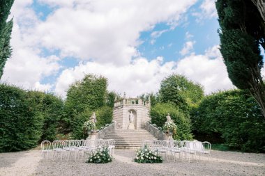 Sıralar dolusu çiçekli sandalyeler parktaki heykelin karşısındaki platformda duruyor. Villa Rizzardi. İtalya. Yüksek kalite fotoğraf