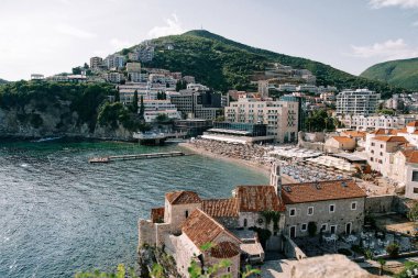 Dağların eteğindeki yeni otellerin yakınındaki eski binaların arkasındaki küçük plaj. Budva, Karadağ. Yüksek kalite fotoğraf