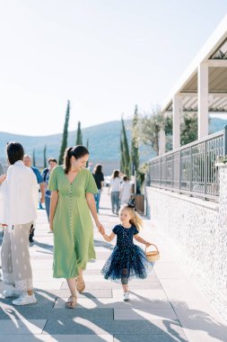 Annem cadde boyunca elinde sepetle cadı kostümü giymiş küçük bir kıza liderlik ediyor. Yüksek kalite fotoğraf