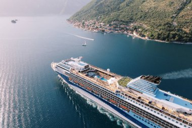 Güvertesinde yüzme havuzları olan büyük bir yolcu gemisi yeşil dağlar boyunca denizde yüzer. Drone. Yüksek kalite fotoğraf