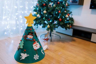 Dekore edilmiş keçeli Noel ağacı odada büyük bir Noel ağacının yanında duruyor. Yüksek kalite fotoğraf