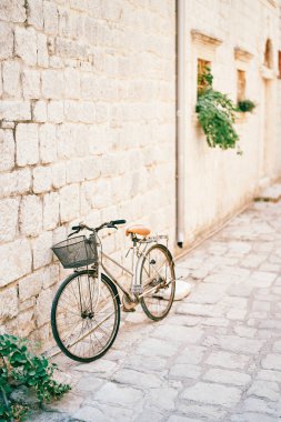 Gidonunda sepet olan bayan bisiklet eski bir evin taş duvarının yanında duruyor. Yüksek kalite fotoğraf