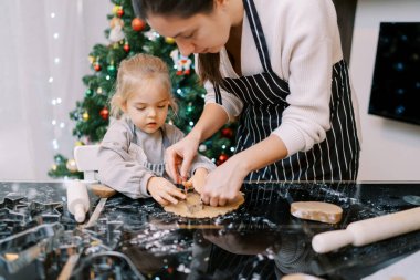 Anne ve küçük kız kurabiye kesiciler masada hamurun üzerine yuvarlanmış. Yüksek kalite fotoğraf