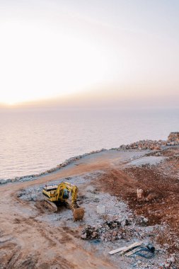 Deniz kıyısındaki bir taş ocağında kazıcı ezilmiş taşları çıkarır. Üst Manzara. Yüksek kalite fotoğraf