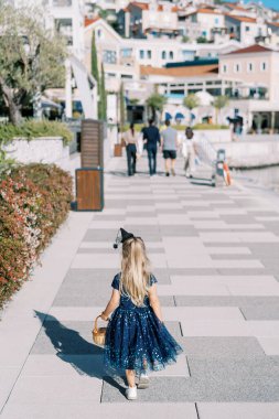 Elinde sepetle caddede yürüyen cadı şapkalı küçük bir kız. Arkadan bak. Yüksek kalite fotoğraf