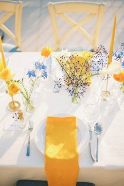 Şenlik masasındaki çiçek buketlerinin yanındaki tabakta sarı peçete. Yüksek kalite fotoğraf