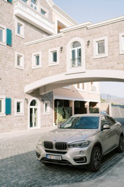 Gümüş renkli BMW SUV otelin avlusunda duruyor. Yolun üzerinde taş bir geçit var. Yüksek kalite fotoğraf