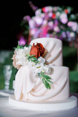 Taze çiçeklerle süslenmiş düğün pastası masanın üzerinde duruyor. Yüksek kalite fotoğraf