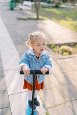 Küçük kız üç tekerlekli scooter 'a biniyor, ağzı açık. Yüksek kalite fotoğraf