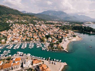 Dağların eteklerinde kırmızı çatıları olan evler lüks bir marinanın karşısında. Porto. Karadağ. Drone. Yüksek kalite fotoğraf