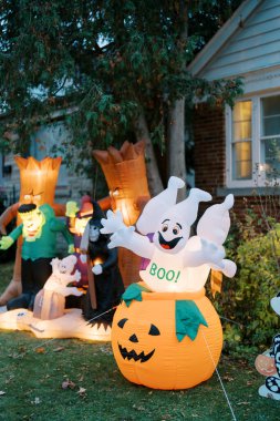 Bahçede şişme karakterlerin olduğu renkli Cadılar Bayramı süslemeleri.