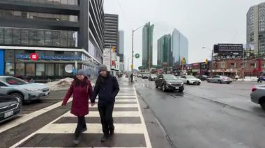 Şehir manzarası yağmurlu bir günde kaldırımda yürüyen yayaları gösteriyor.