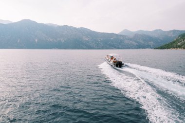 Beyaz motorlu yat, bir dağ sırasının yakınında denizde yol alıyor. Arkadan bak. Drone. Yüksek kalite fotoğraf