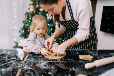 Anne ve küçük kız kurabiye kesiciler masada hamurun üzerine yuvarlanmış. Yüksek kalite fotoğraf