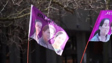 Canlı bir toplantıda, renkli bayraklar çeşitli görüntüler ve mesajlar sergiliyor.
