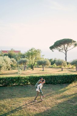 Adam yeşil çimlerde kadını sırtında taşıyor. Yan görüş. Yüksek kalite fotoğraf