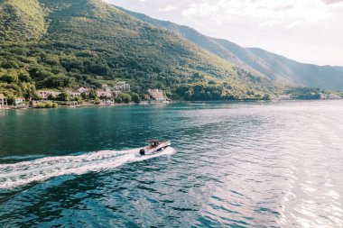 Sahilde bir tatil köyü olan yeşil dağların arka planına karşı denizde bir yat seferi düzenlenir. Yüksek kalite fotoğraf