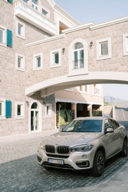 Gümüş renkli BMW SUV otelin avlusunda duruyor. Yolun üzerinde taş bir geçit var. Yüksek kalite fotoğraf