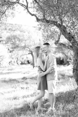Adam parkta bir ağacın yanında dururken neredeyse onu öpecek olan kadına sarılıyor. Siyah beyaz fotoğraf. Yüksek kalite fotoğraf